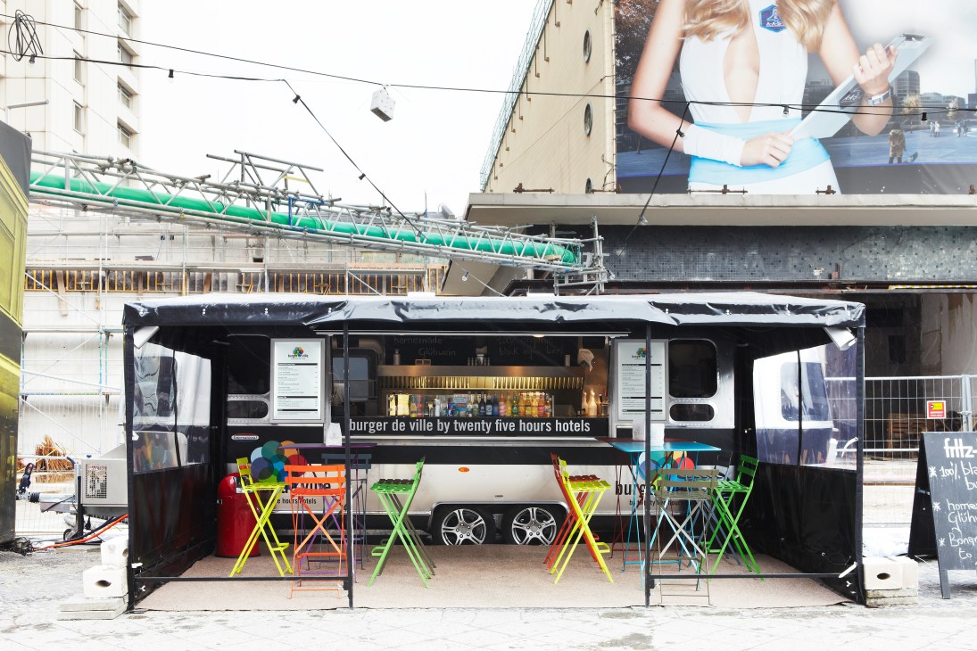 Burger de Ville Airstream food trailer with colorful chairs and signage in Berlin construction site.