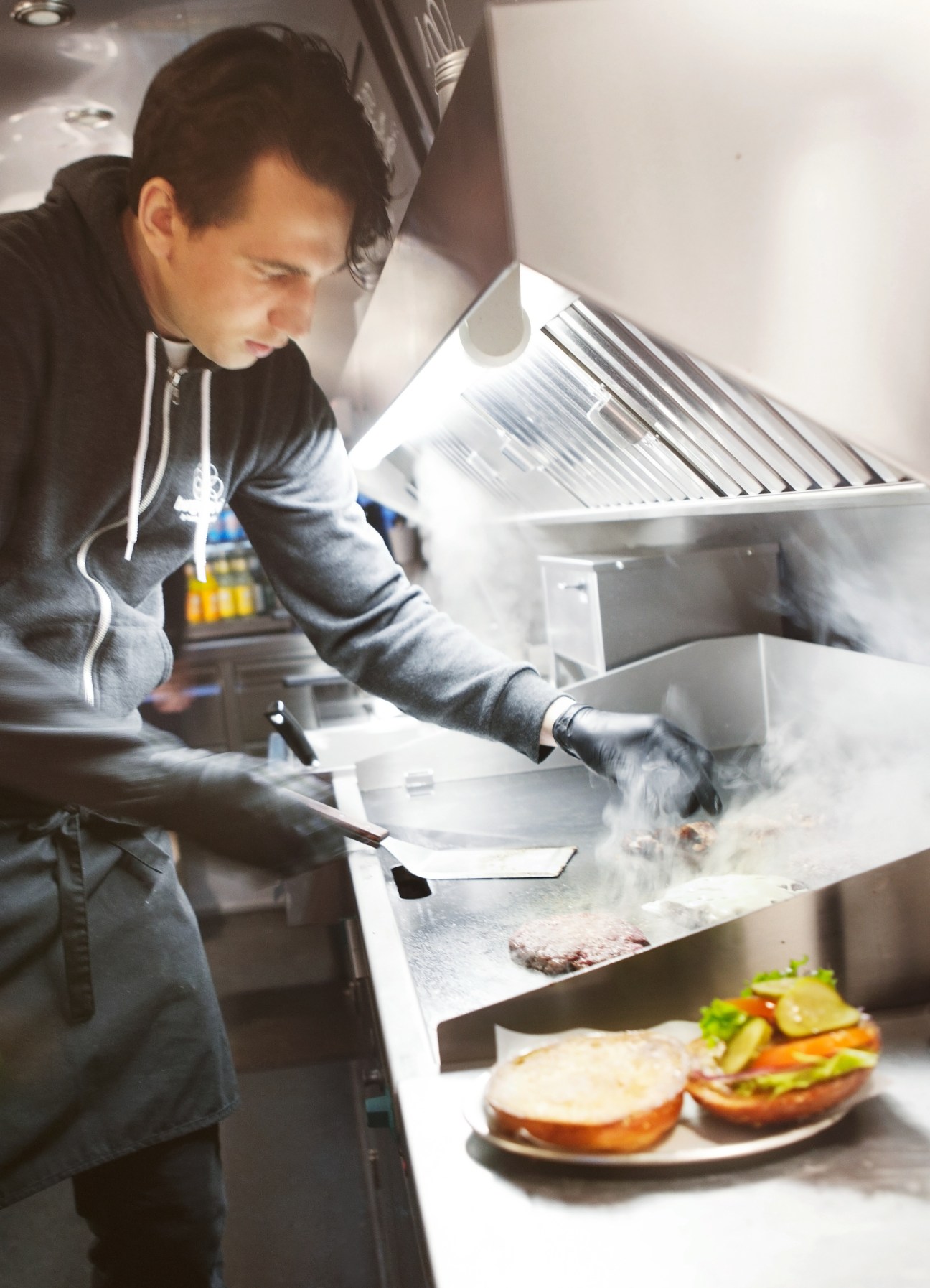 Chef preparing a burger at Burger de Ville mobile kitchen in Berlin.