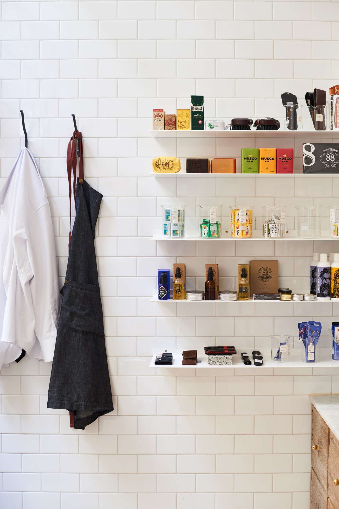White subway tiled wall with floating shelves displaying grooming products, bottles, and accessories neatly organized.