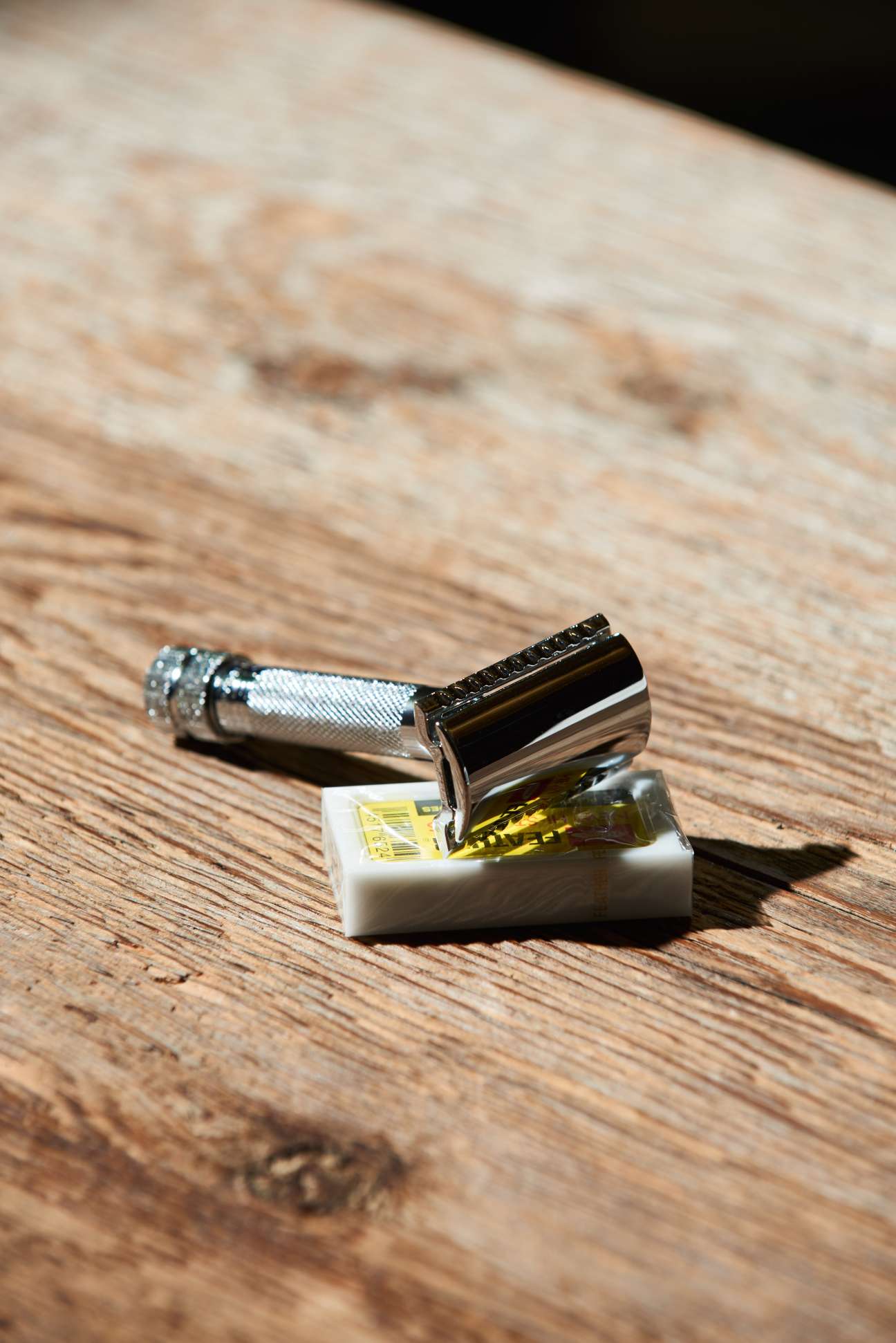 Dovo's double-edged safety razor with chrome head and textured handle displayed on wooden surface with soap.
