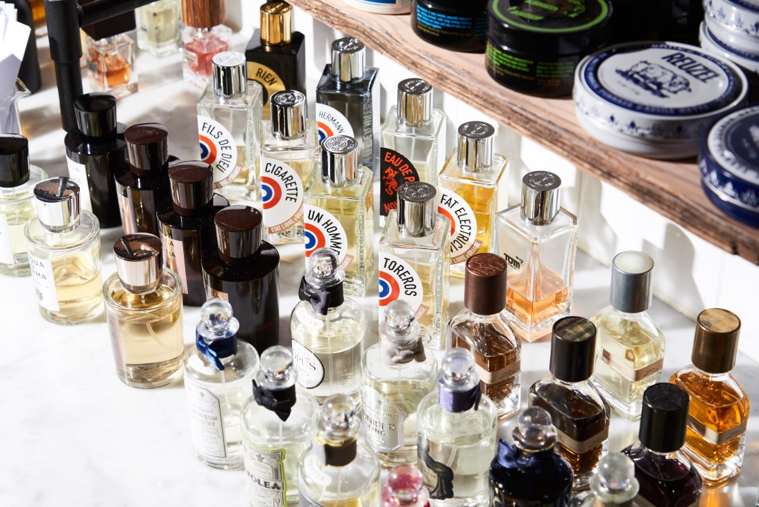 Men's grooming products including colognes, fragrances and barbershop supplies neatly arranged on white shelving.