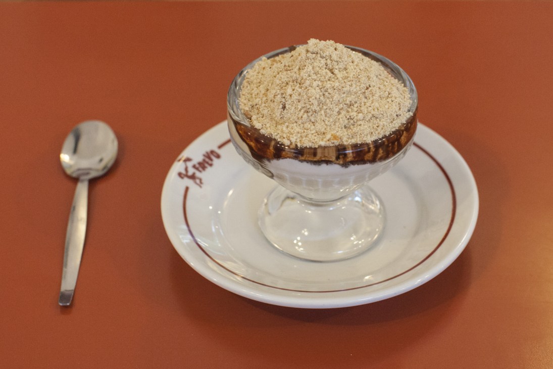 Capricho dessert with vanilla ice cream, chocolate syrup, marshmallow and toasted manioc flour in a glass bowl.