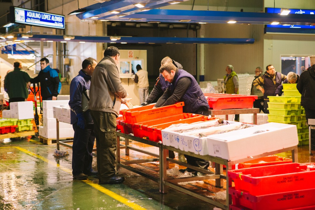 Fish merchants inspect and handle fresh seafood at Mercamadrid market in Madrid.