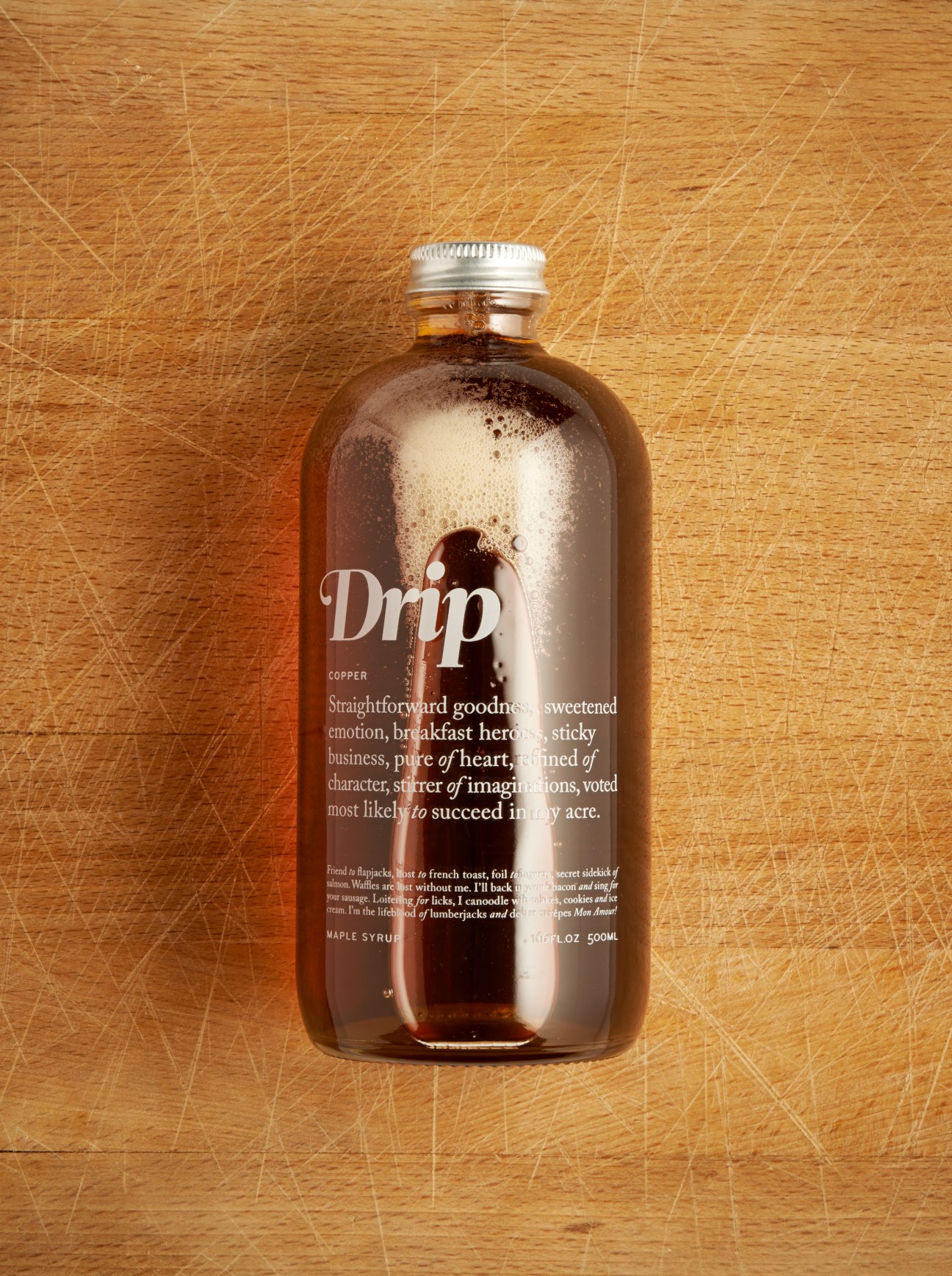 Drip Maple maple syrup bottle with silver cap on wooden surface