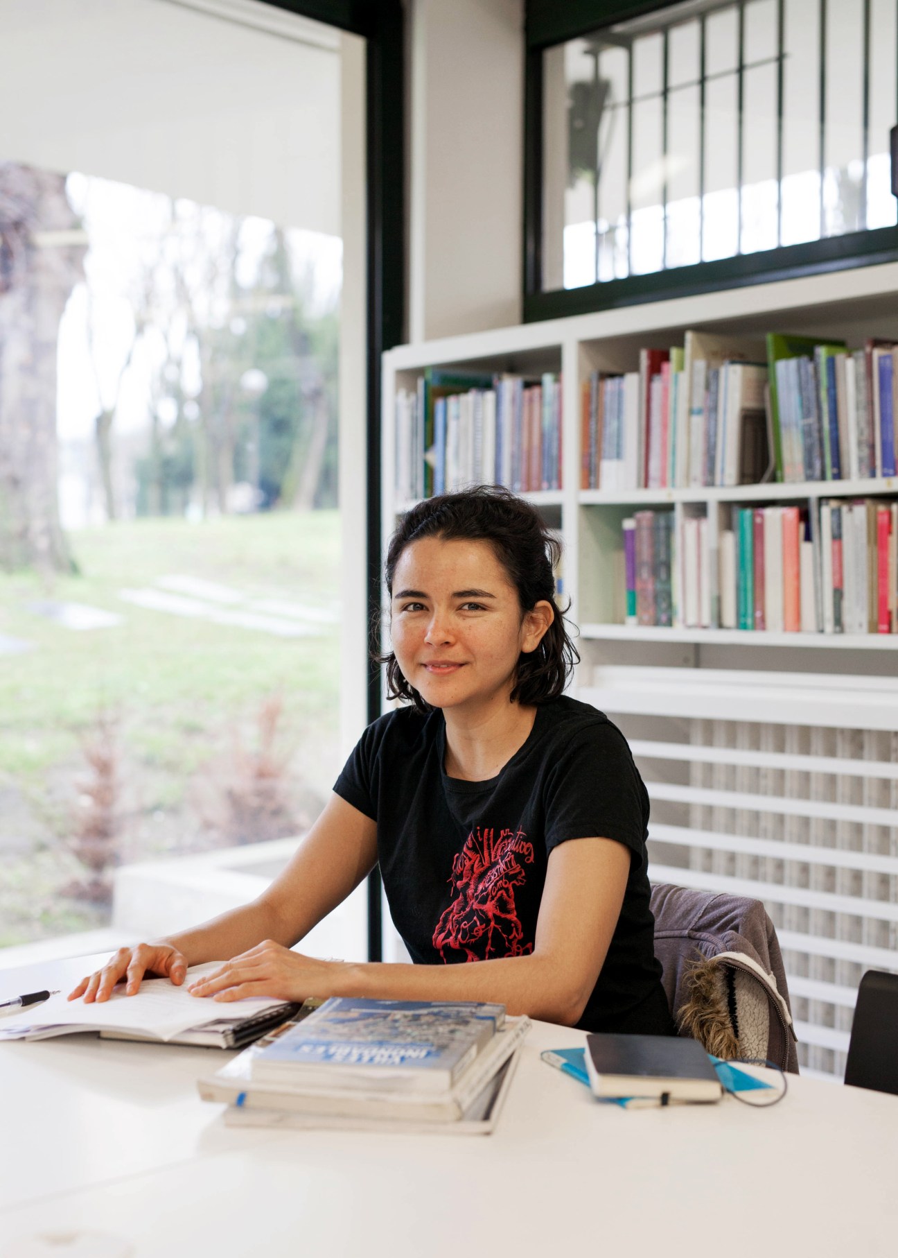 Student seated at a desk in the Maison Mexique library with bookshelves visible behind.