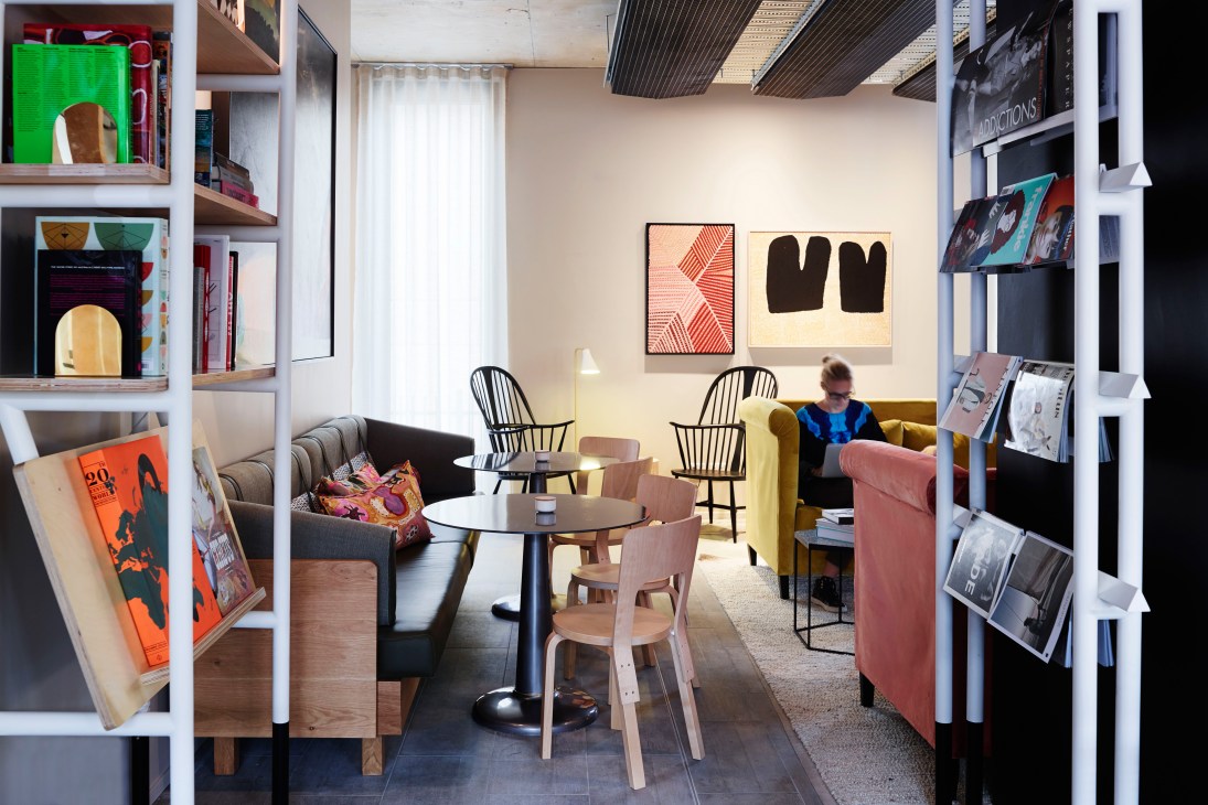 Interior lounge space at Alex Hotel with shelving, artwork, seating areas and natural lighting.