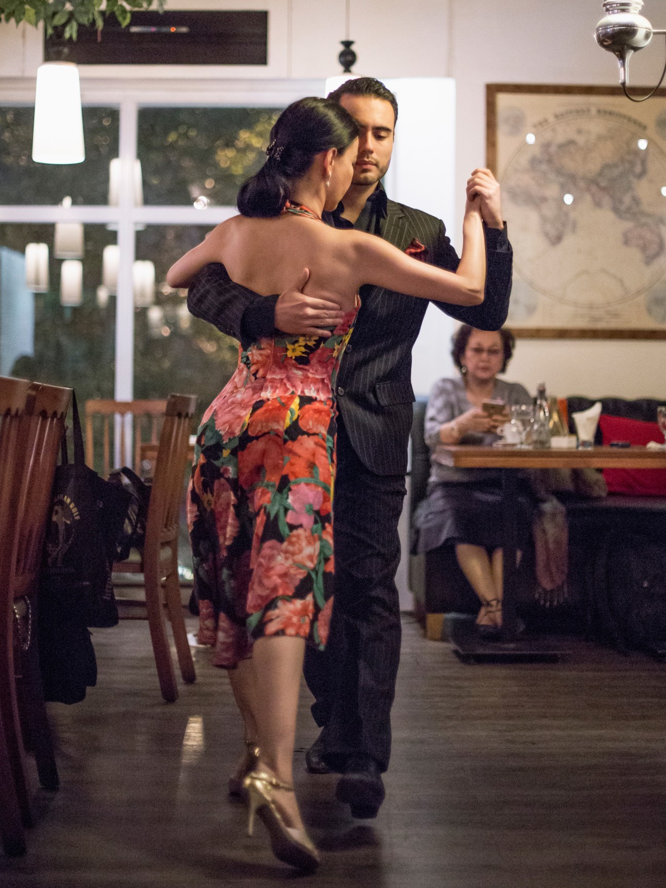 A couple performs tango in an indoor venue in Jakarta, with the woman wearing a floral dress and the man in formal attire.