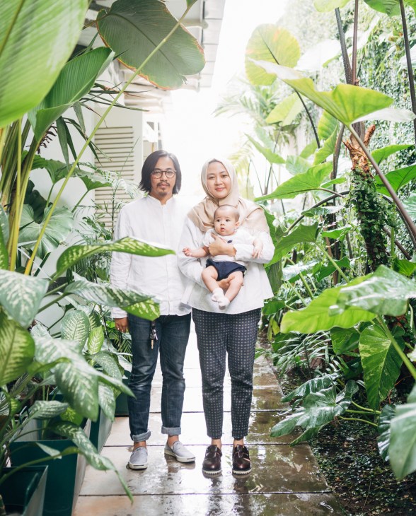 ORE founder Alek Kowalski with his wife Dewi and daughter Hamida standing in a lush plant-filled corridor.