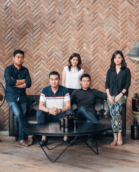 Five young entrepreneurs pose in front of a herringbone brick wall at RestoSociety Complex in Surabaya.