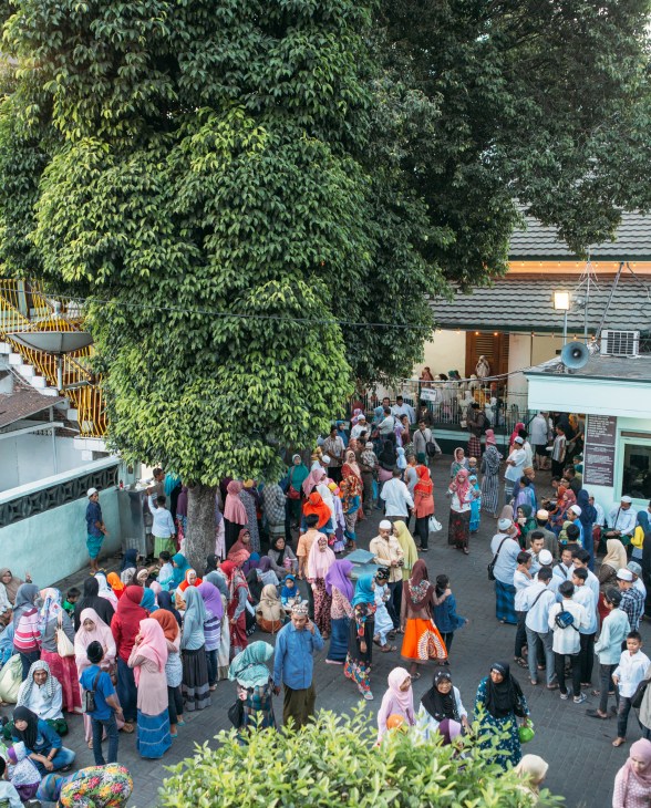 Aerial view of crowds gathering in Ampel, Surabaya's Arab quarter, beneath a large ivy-covered tree.