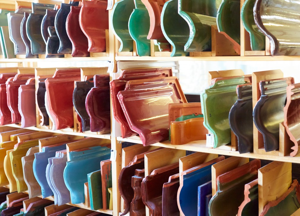 Shelves displaying glazed roofing tiles in various colors including red, green, blue, and yellow.