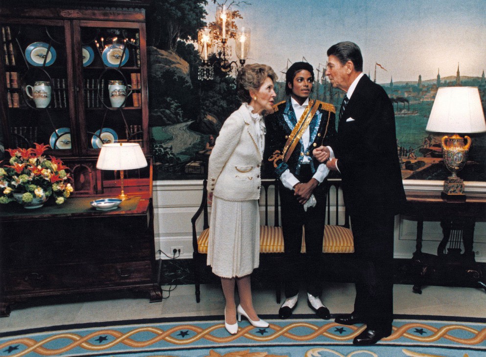 Nancy Reagan, Michael Jackson and Ronald Reagan in an ornate room with period furnishings and a cityscape backdrop.
