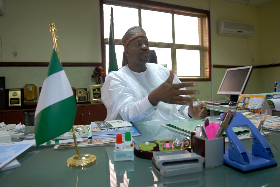 Aliyu Modibbo Umar, Abuja's minister, sits at his desk in an office with the Nigerian flag.