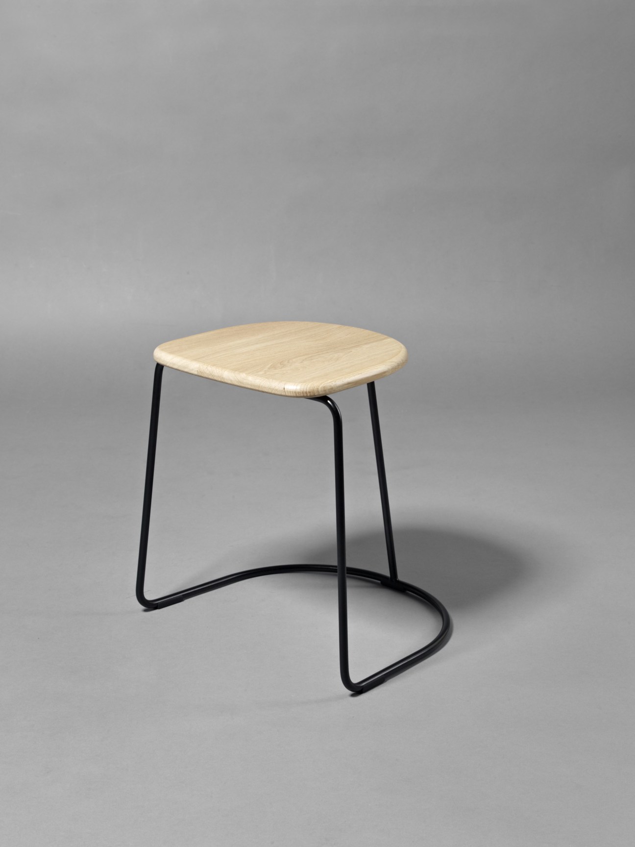 Minus Tio Citizen Ghost stool with light wood seat and black steel frame on grey background.