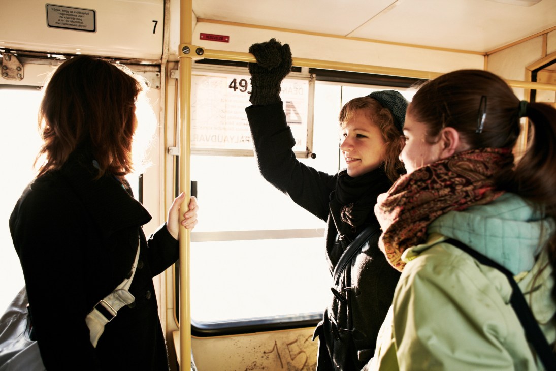 Commuters inside a Budapest tram, with a young woman holding the overhead rail.