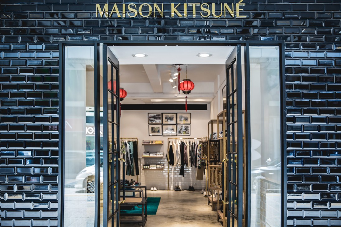 Maison Kitsuné storefront in Hong Kong with red lanterns and wooden cabinets inside.