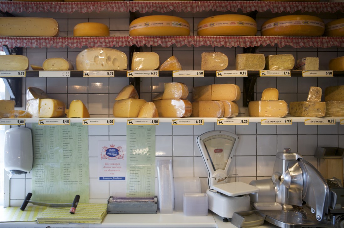 De Ridder cheese shop display with various Dutch cheeses on shelves and counter equipment.