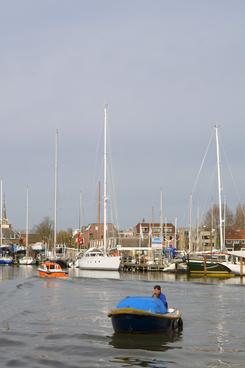 Sailboats moored at Niewendammerdijk harbour with traditional Dutch buildings along the waterfront.