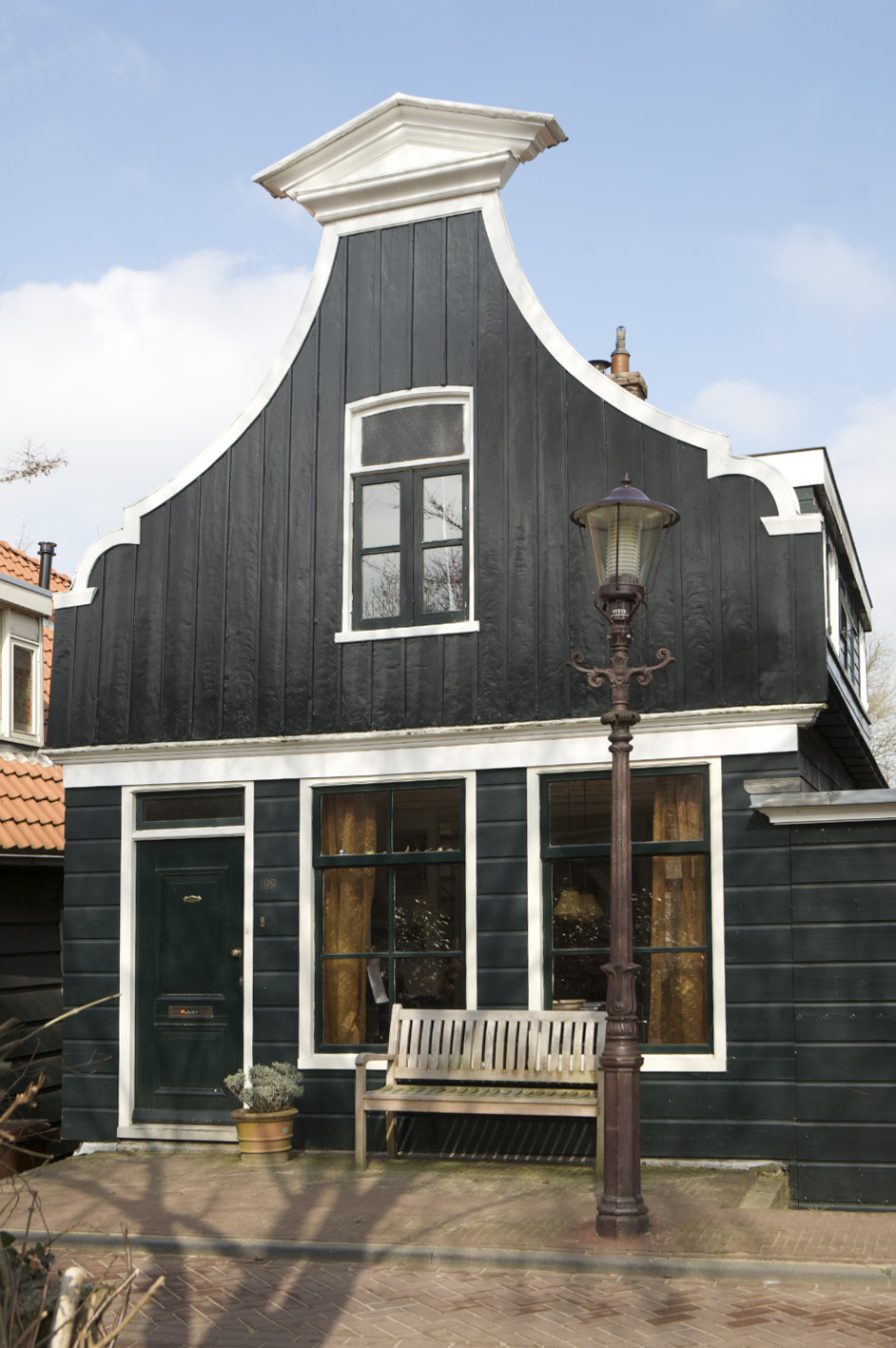 Traditional Dutch wooden house with distinctive curved gable roof, dark timber cladding and white trim on Northern IJ Bank.