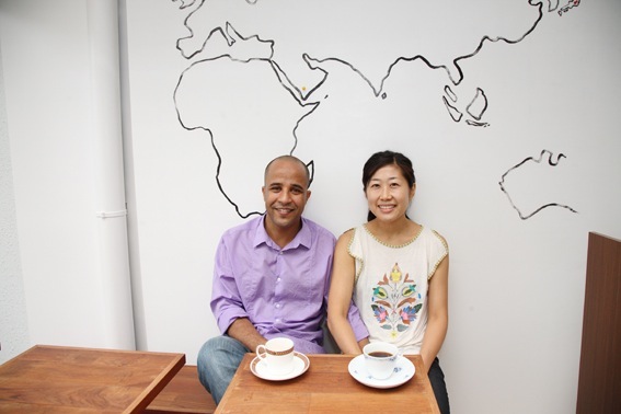 Hussein Ahmed and Maiko Miyake, owners of Mocha Coffee in Tokyo, seated at a wooden table with coffee cups.