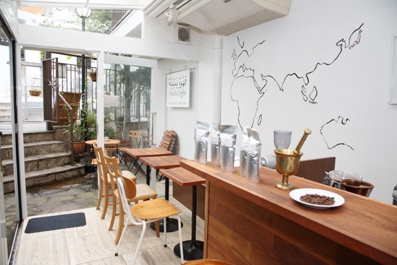 Interior of Mocha Coffee in Tokyo showing wooden counter, chairs, skylight, and line drawing on white wall.