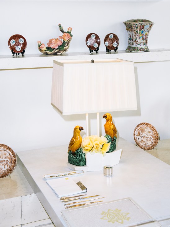 Leonore Annenberg's writing desk at Sunnylands displaying decorative items including a ceramic parrot lamp, ornamental plates, and writing implements.