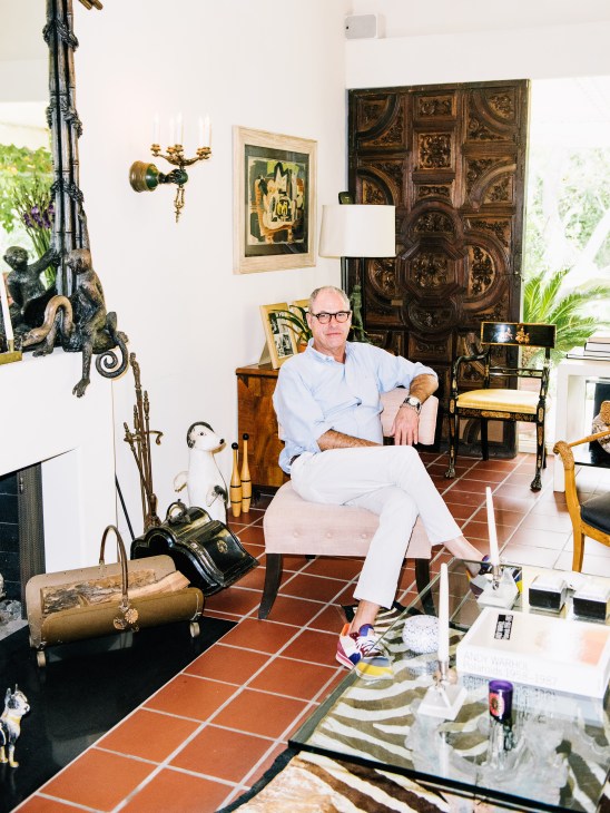 Interior designer Carey Maloney seated in an eclectic living room with vintage furnishings and artwork.