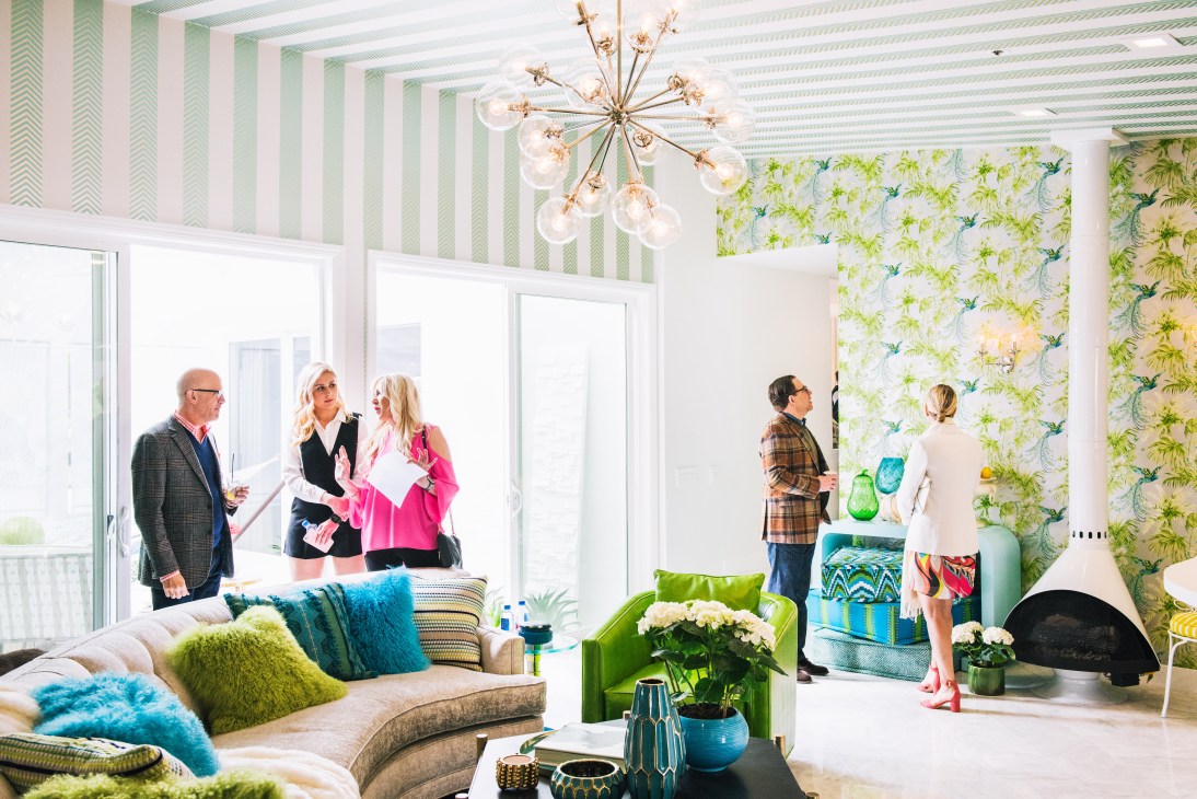 Colorful mid-century modern living room at Villa Golightly with striped walls, geometric patterned wallpaper, and visitors admiring the space.