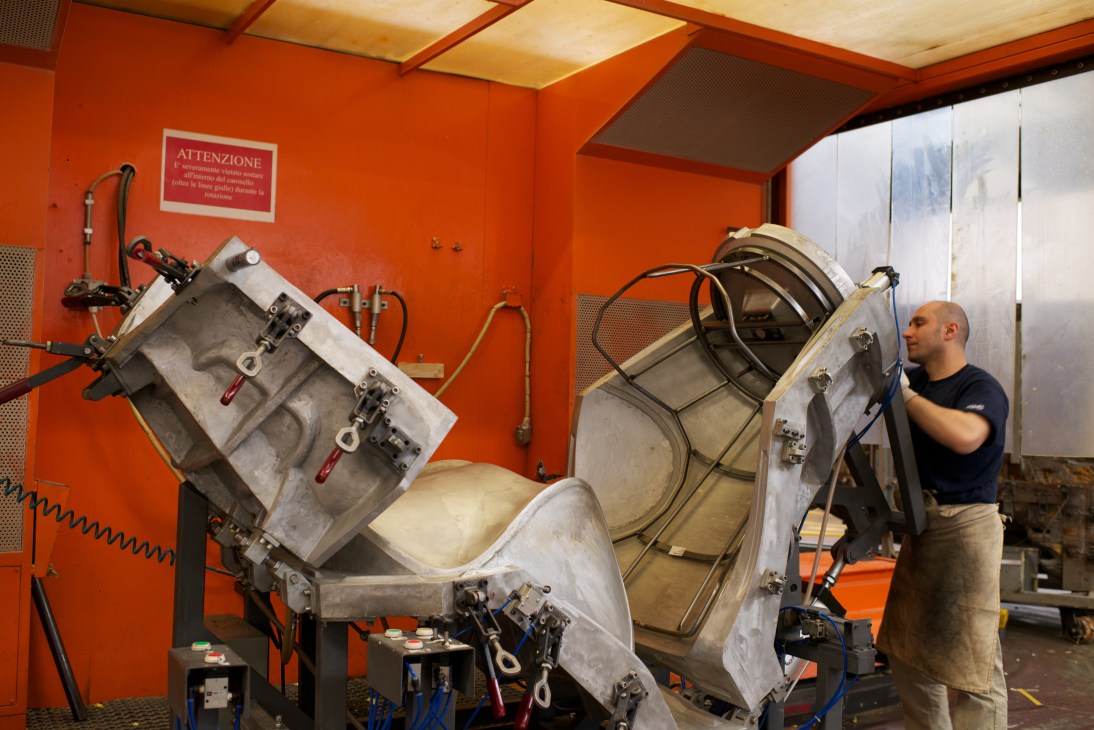 Worker adjusts large metal moulds used for injection-moulding polyurethane foam furniture at B&B Italia factory.