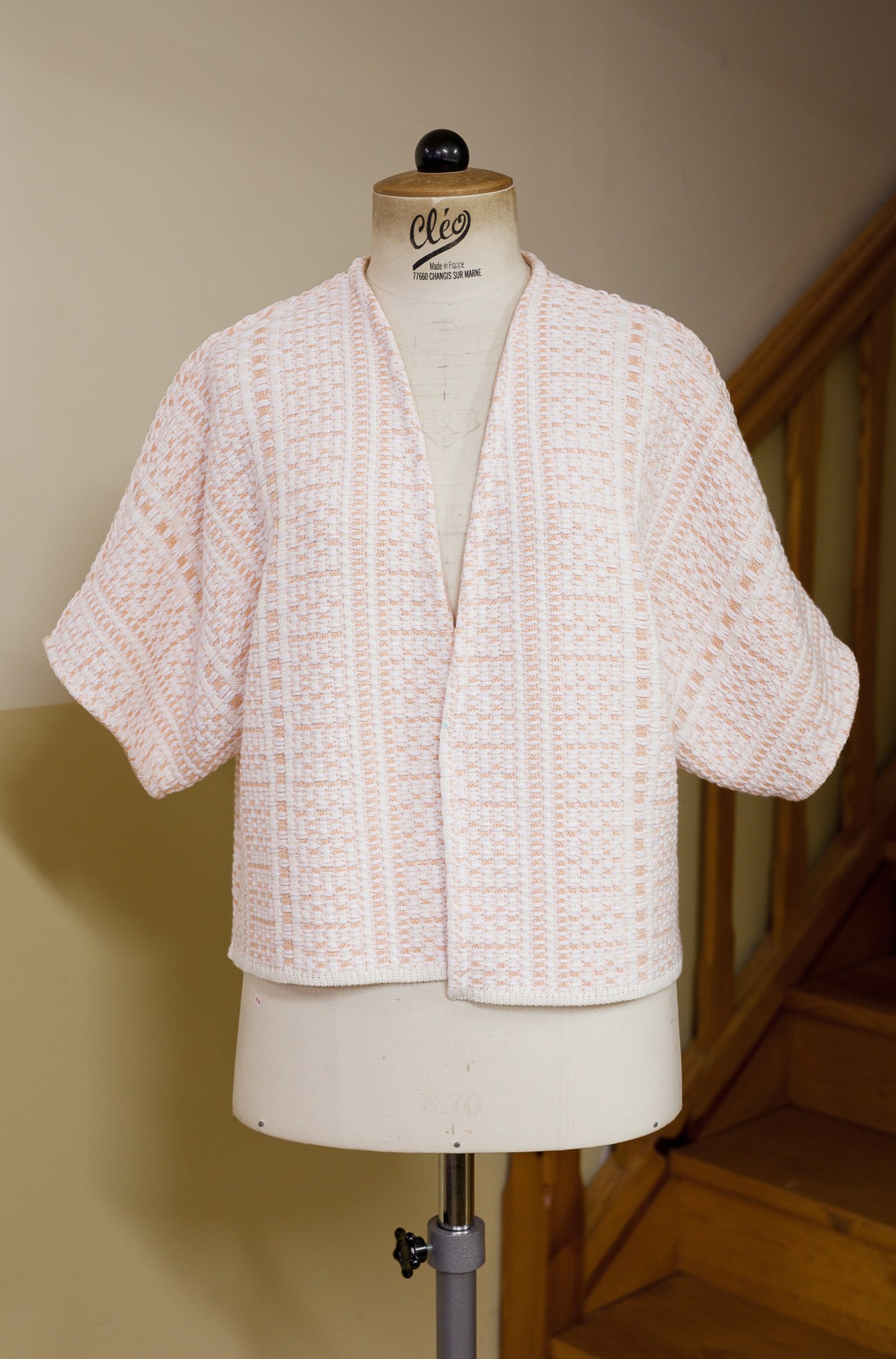 Pink and cream textured cardigan displayed on a dress form with Molli branding.