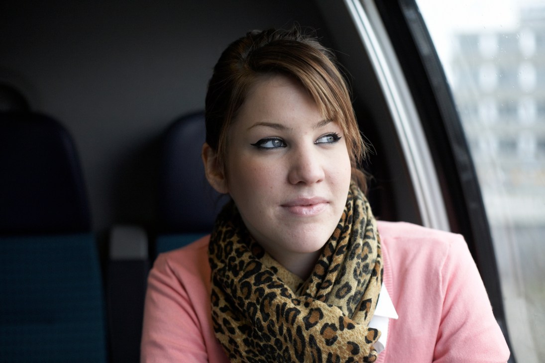 Sophie Frei, a Swiss flight attendant, seated inside an SBB train car by a window.