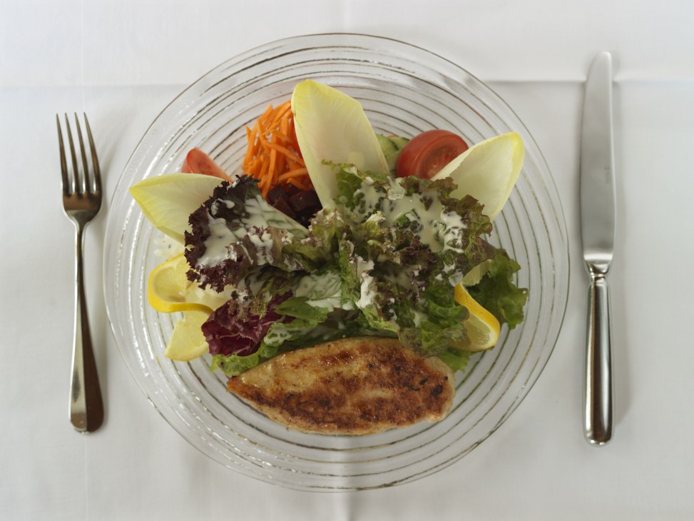 Fitnessteller plate with grilled chicken breast, shredded carrots, cucumber, endive, tomato, sweetcorn, beetroot, and lettuce with dressing.