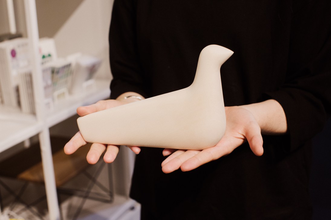 Hands holding a white sculptural bird-shaped object, L'oiseau by Vitra