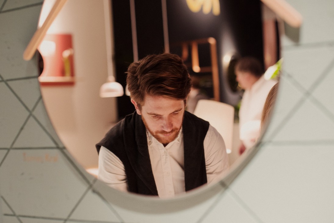 Man viewed through a circular opening at the Hartô stand at IMM Cologne furniture fair.