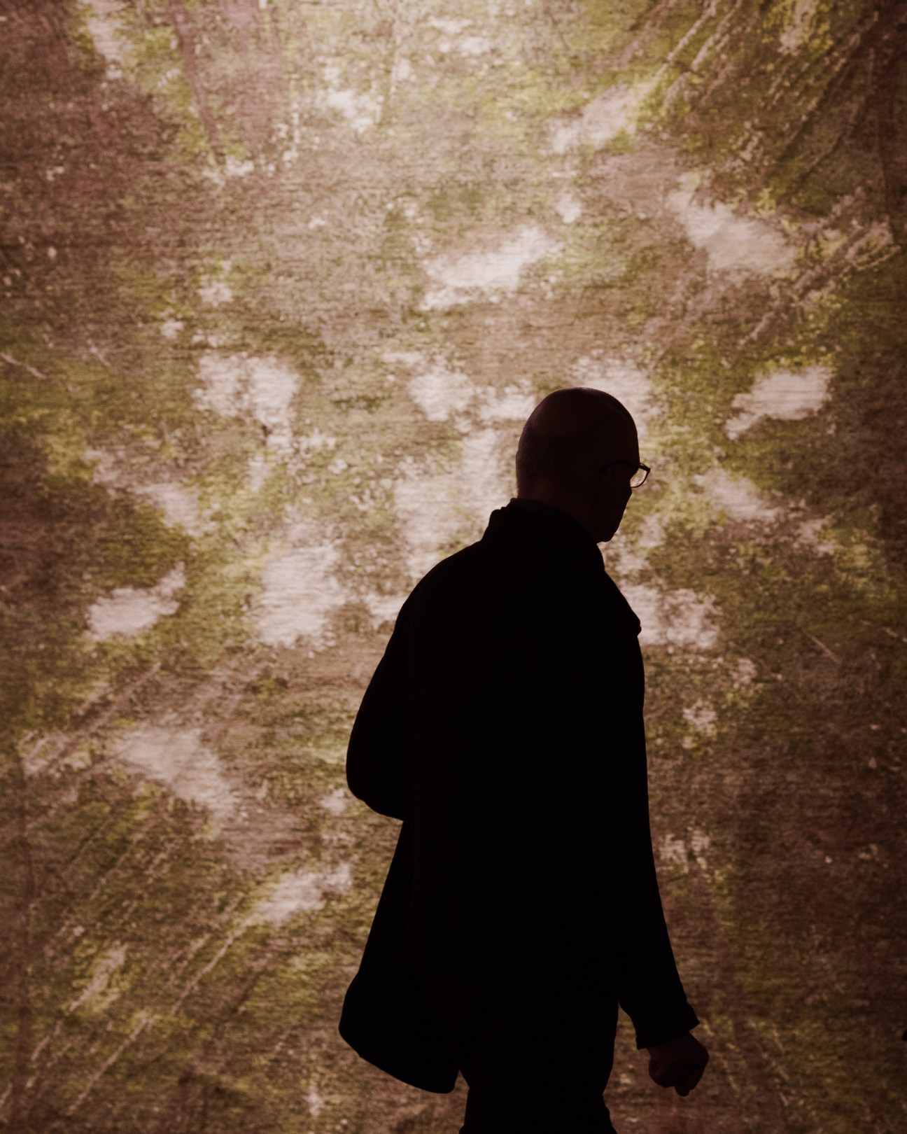 Person in silhouette viewing a textured wall installation at IMM Cologne furniture fair.