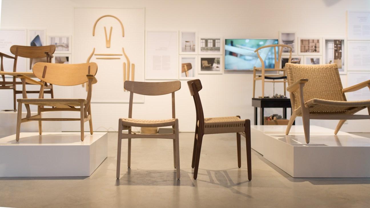 CH23 chair by Carl Hansen & Søn displayed at IMM Cologne furniture fair, with multiple wooden chairs on white platforms.