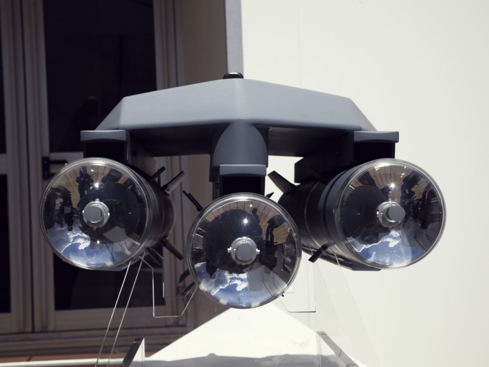 Three circular thermal imaging or surveillance camera lenses mounted on a black platform against a white building.