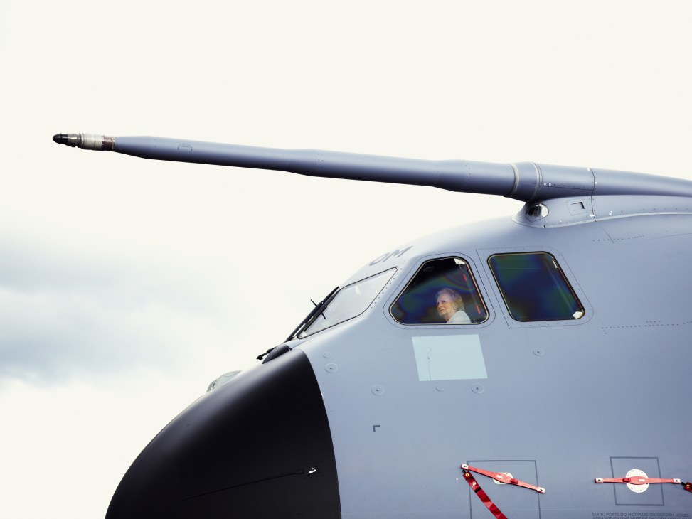 Pilot visible in cockpit window of Airbus A400M Atlas military transport aircraft with missile pod mounted above.