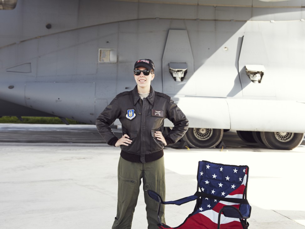 US Air Force officer in flight suit standing in front of large military transport aircraft.