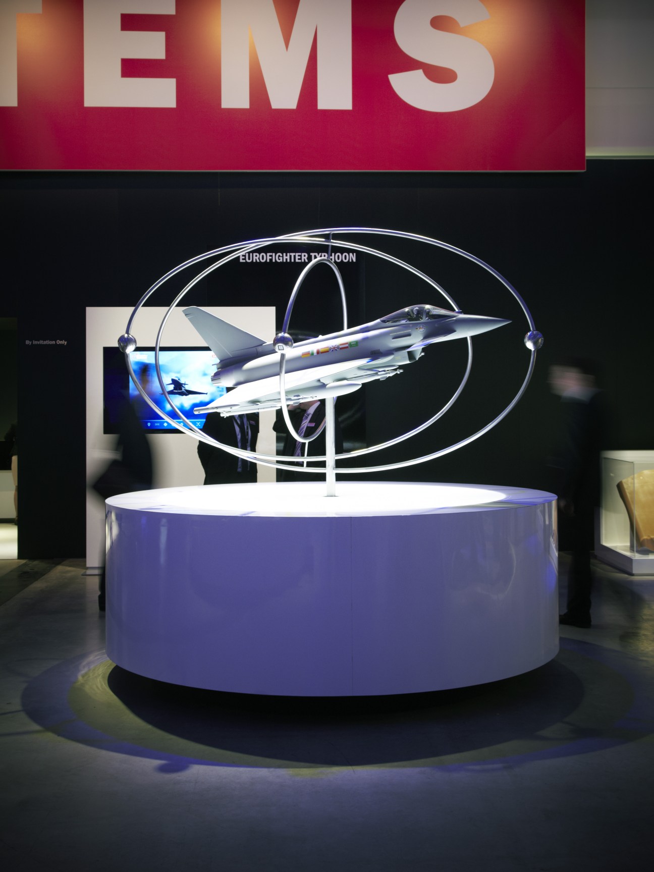 Eurofighter Typhoon fighter jet model displayed on illuminated circular platform at air show.