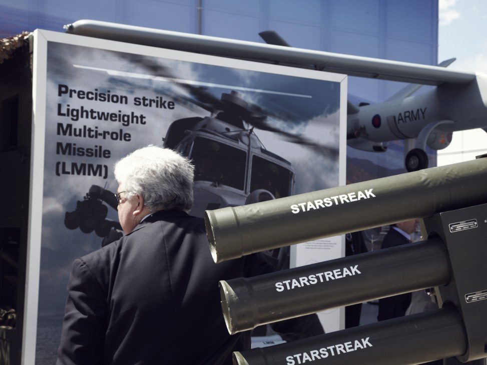 Man examining Starstreak missiles displayed at Farnborough air show with LMM missile poster behind.