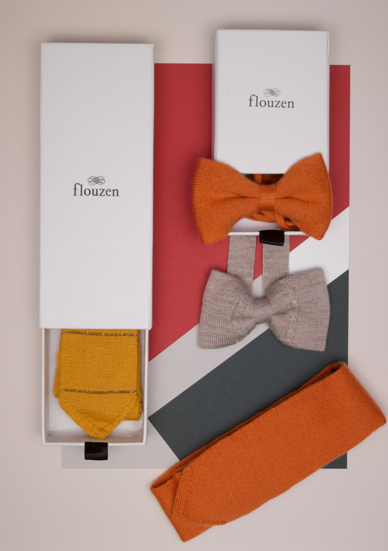 Flouzen cashmere bowties and socks displayed with branded packaging in orange and neutral tones.