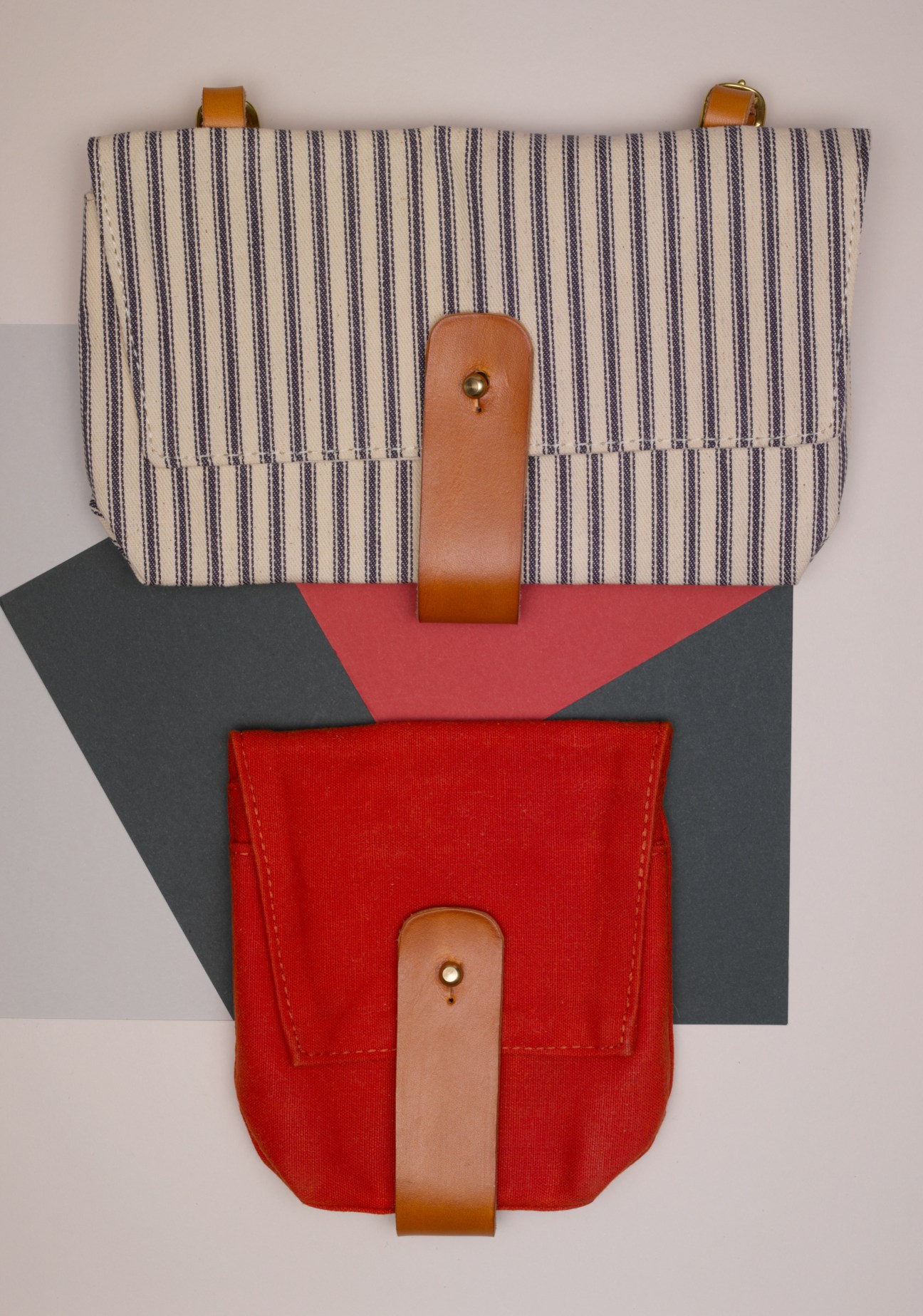 DNTX hand-dyed bike bags in red and striped fabric with leather straps displayed flat.