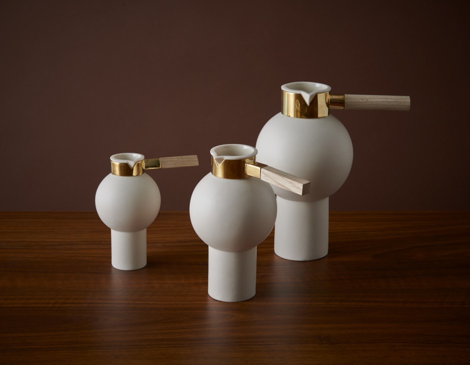 Three porcelain-and-brass pitchers with spherical white bodies, brass bands, and wooden handles by Anna Karlin.