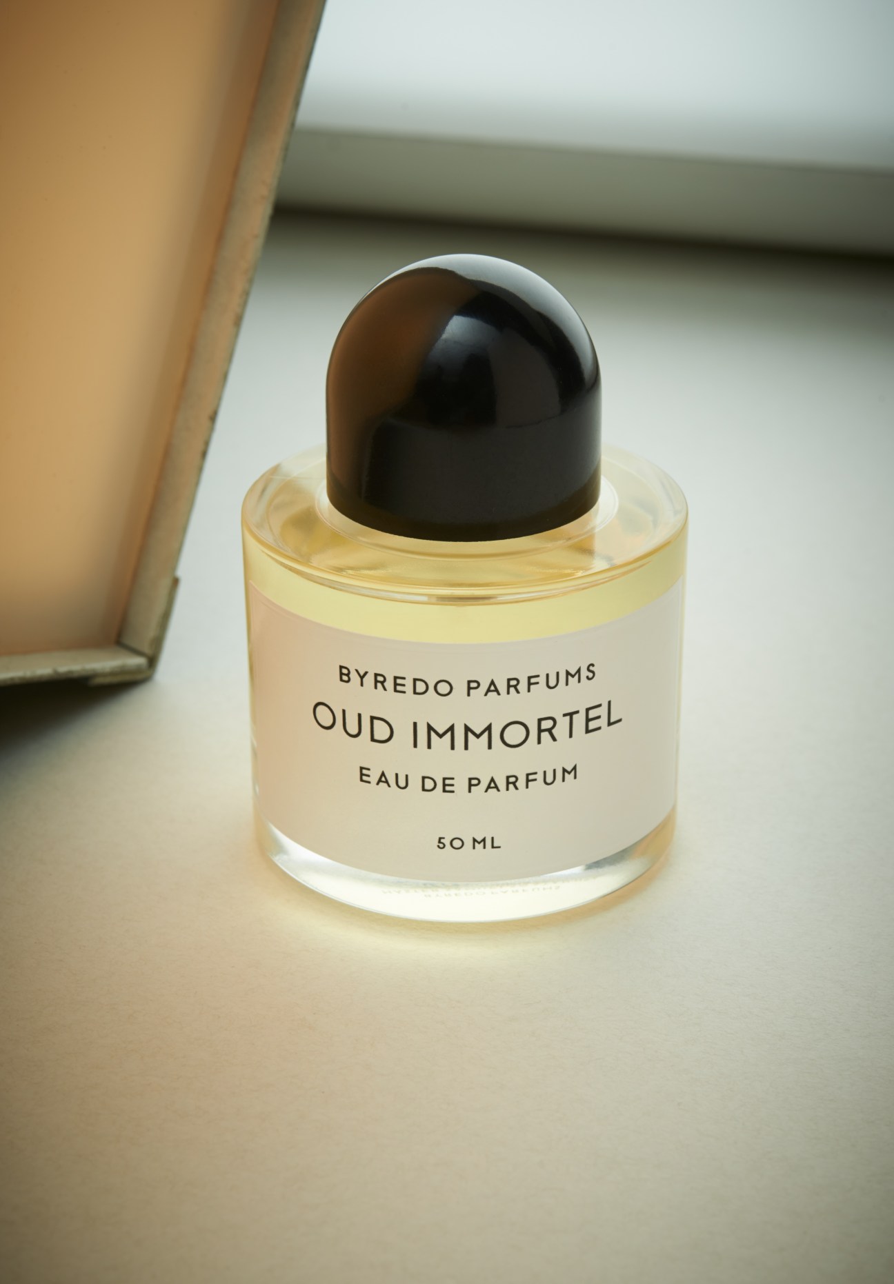 Byredo Parfums Oud Immortel eau de parfum bottle with black cap and pale yellow liquid.