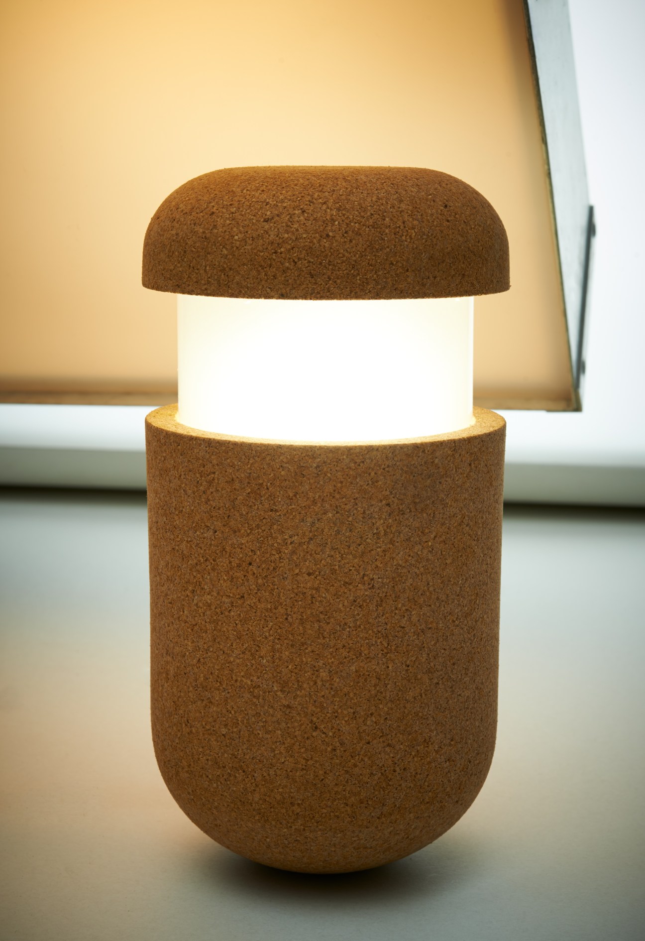 Mr Wobbles lamp with cork capsule-shaped body and illuminated white center against warm background