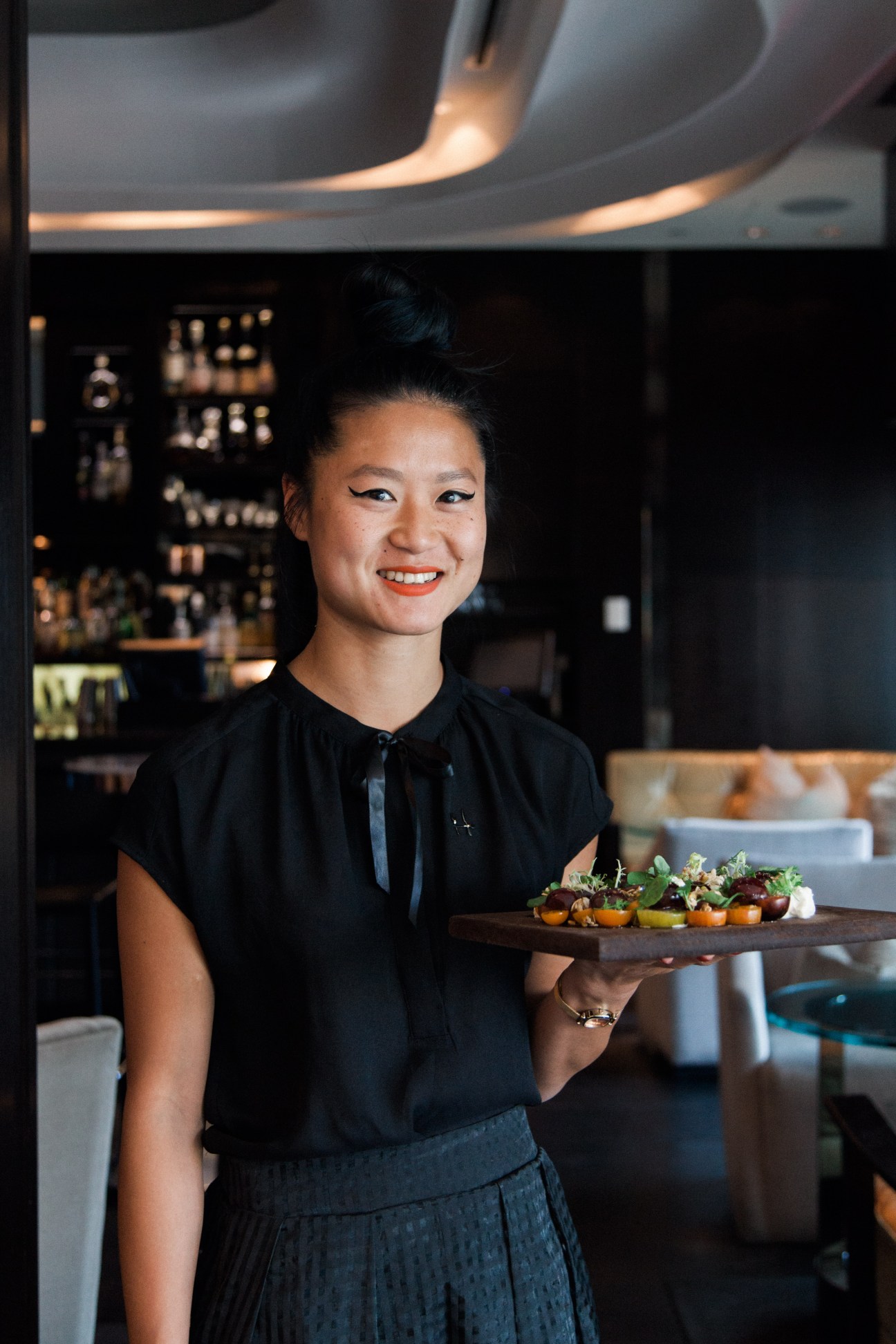 Server holding a wooden plate of appetizers at Hawksworth restaurant in Vancouver.