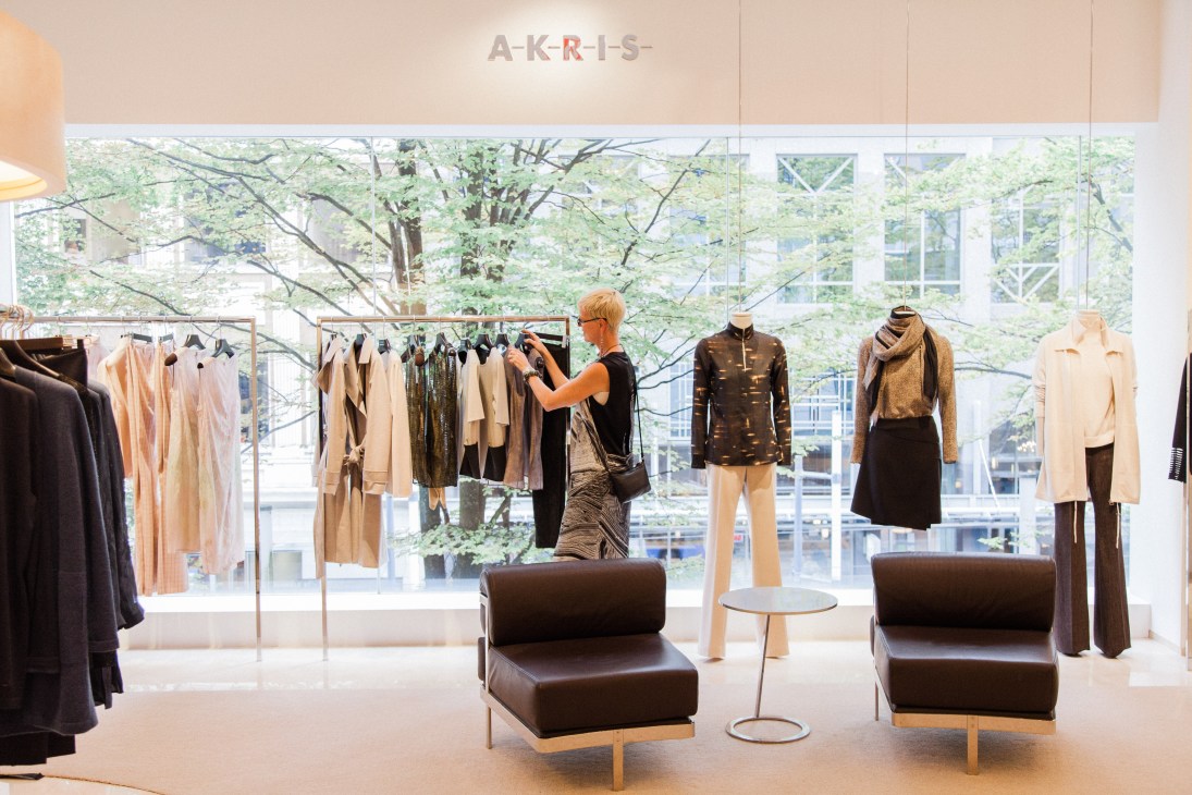 Interior of Holt Renfrew boutique with clothing displays, mannequins, and brown leather seating.