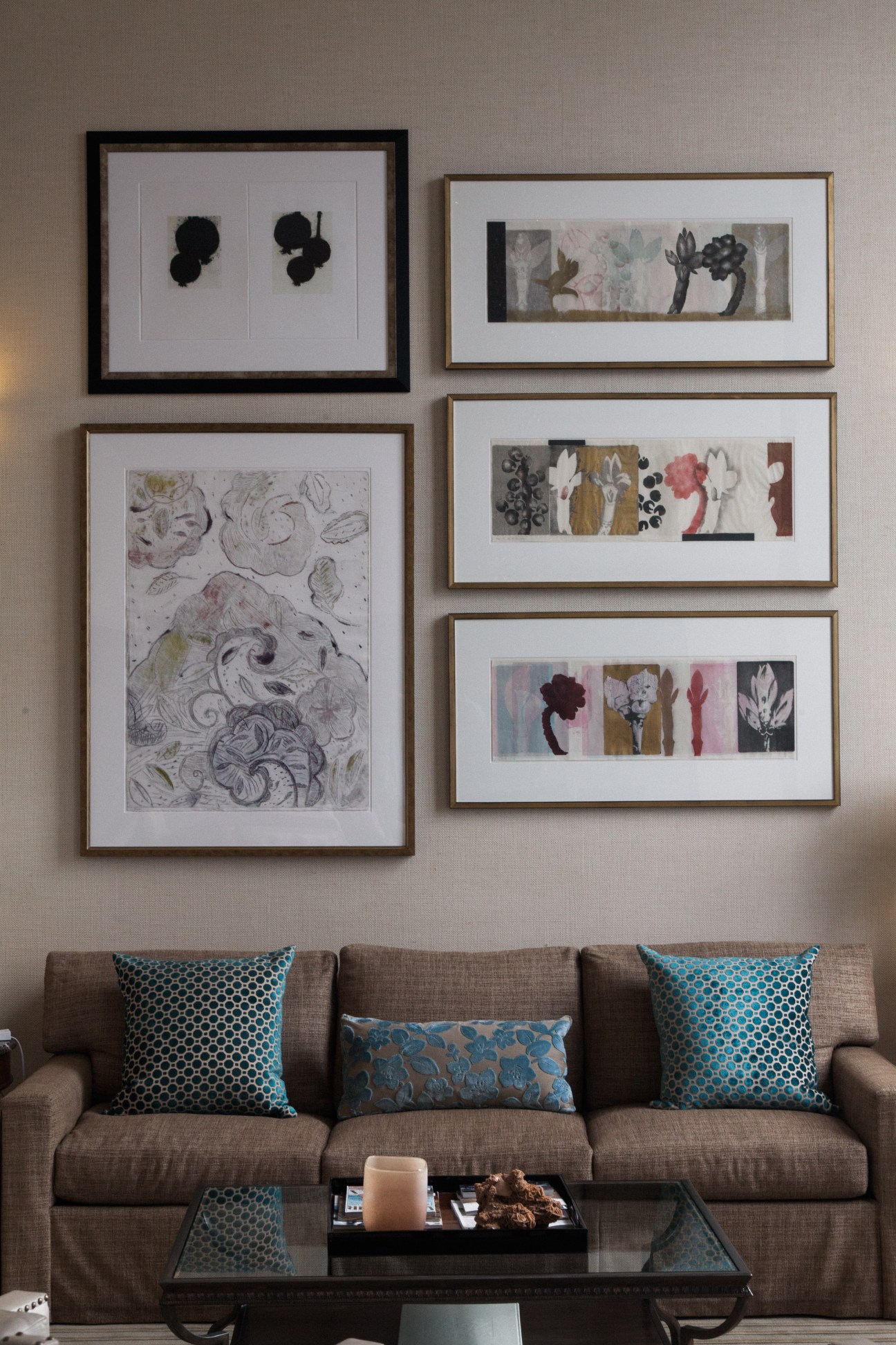 Four Seasons hotel interior with framed botanical artwork above a beige sofa with patterned cushions.