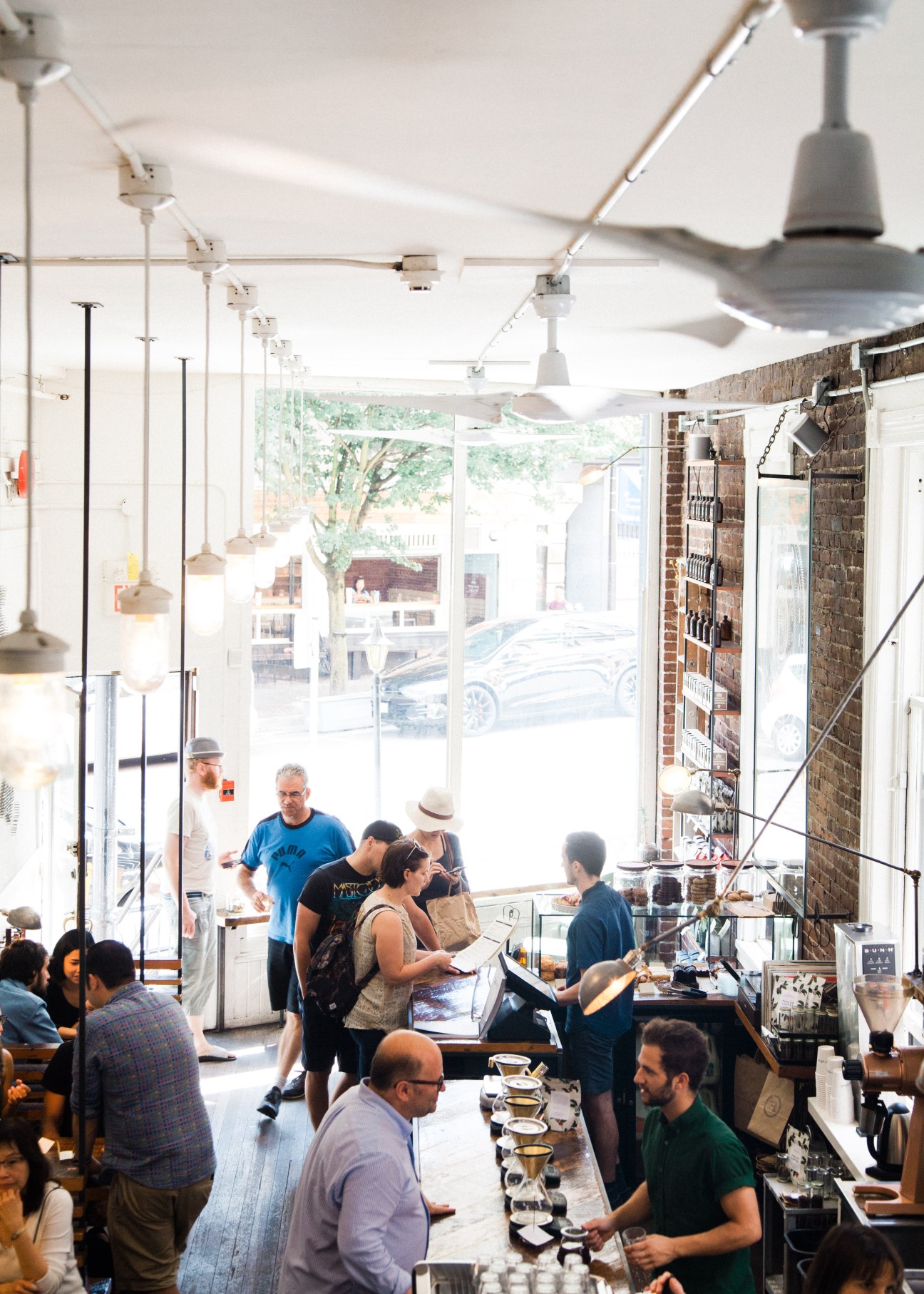 Interior of Revolver Coffee café with customers at counter and large windows overlooking street.